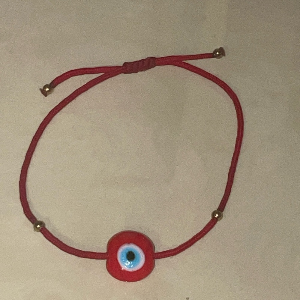 Adjustable evil eye red string bracelet with gold beads.
